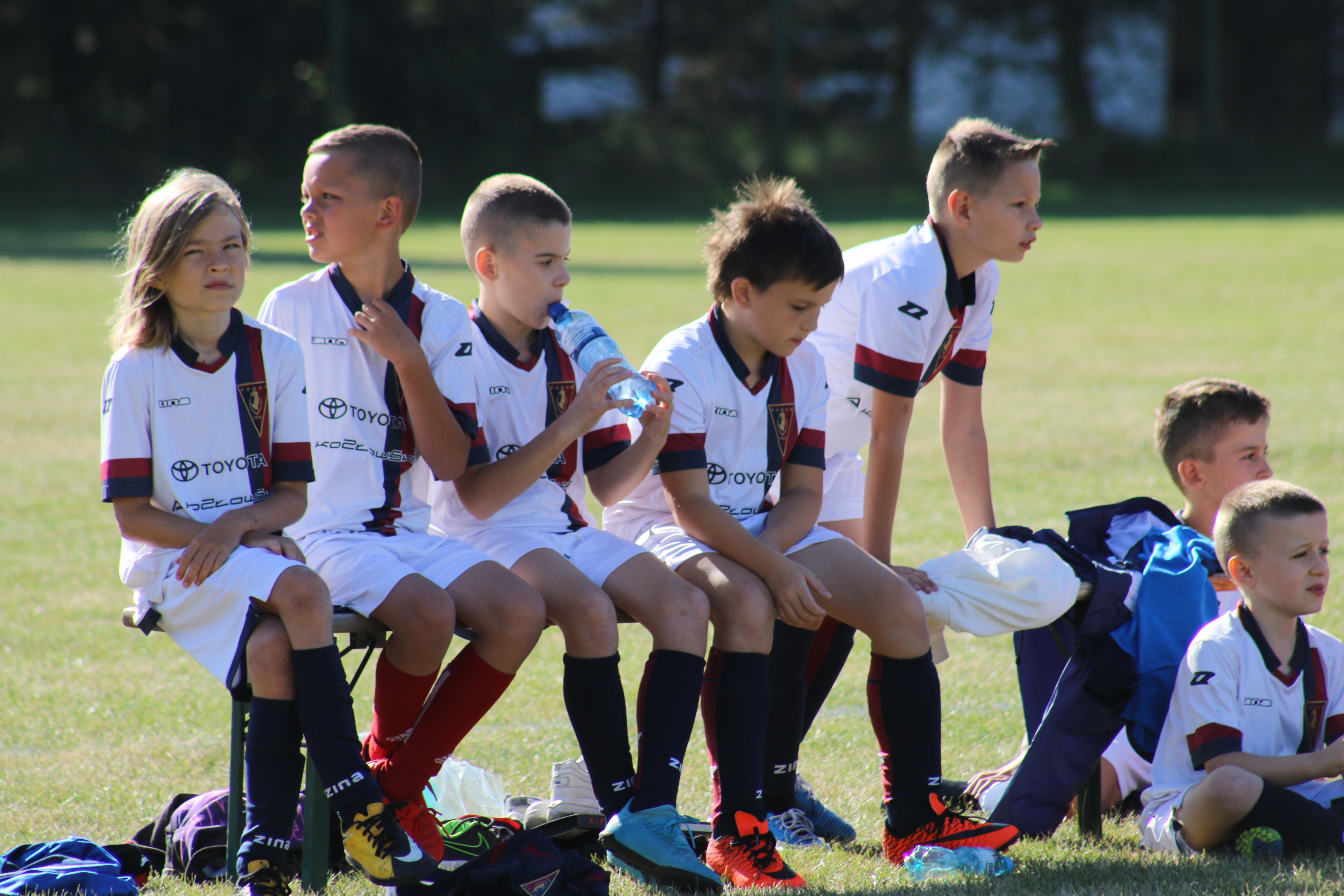 dzieci siedzące na ławce w trakcie turnieju piłkarskiego ośrodków "Kibice Razem"