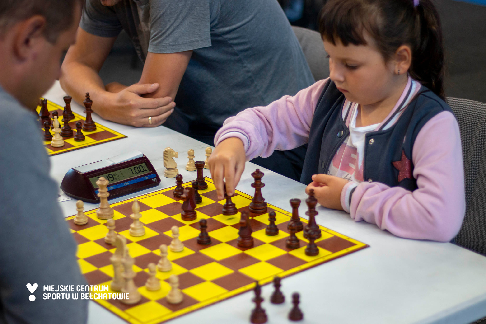 na zdjęciu widoczna jest dziewczynka wykonująca ruch na szachownicy podczas turnieju szachów szybkich pn.: "Gambit Bełchatowski"