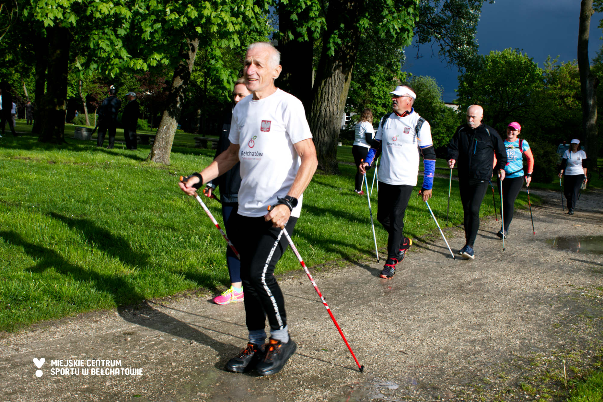 na zdjęciu widoczni są uczestnicy Warsztatów Nordic Walking Bełchatów, którzy maszerują z kijkami w ramach szkolenia i treningu